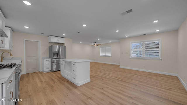 kitchen with light hardwood / wood-style flooring, a center island, appliances with stainless steel finishes, and white cabinets