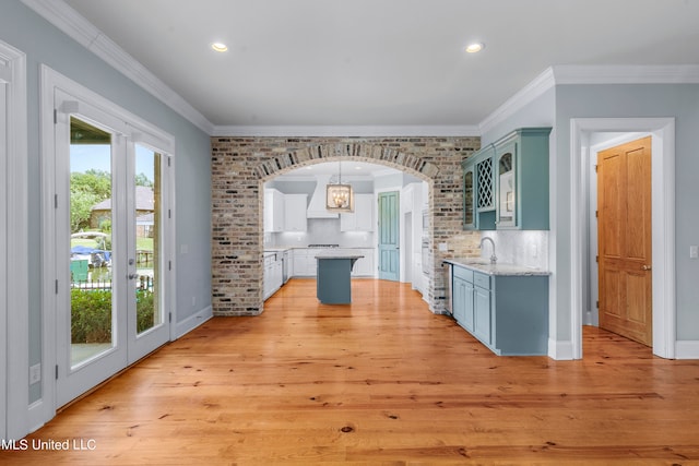 kitchen featuring pendant lighting, ornamental molding, light wood-type flooring, and a kitchen island