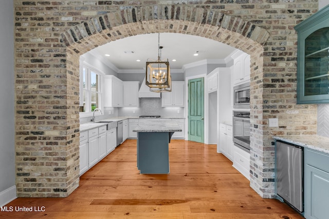 kitchen featuring a kitchen island, white cabinetry, stainless steel appliances, light stone counters, and light hardwood / wood-style flooring