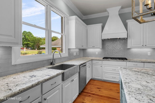 kitchen featuring white cabinetry, stainless steel appliances, premium range hood, and plenty of natural light