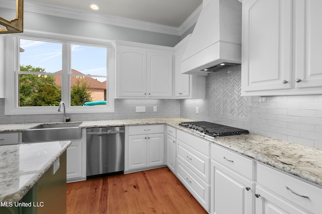 kitchen featuring custom exhaust hood, white cabinets, sink, and appliances with stainless steel finishes