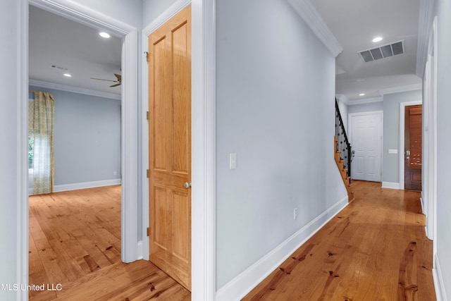 hall with ornamental molding and light hardwood / wood-style floors