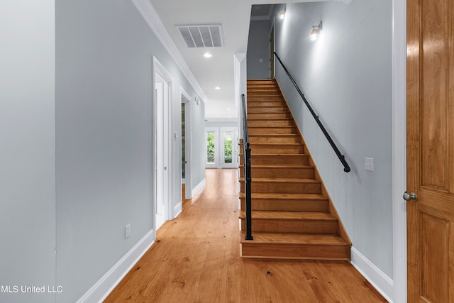 stairs featuring french doors, ornamental molding, and hardwood / wood-style floors