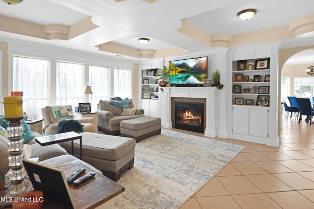 living room with light tile patterned floors, a fireplace, and built in features