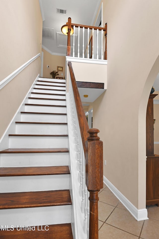 stairs with tile patterned flooring and ornamental molding