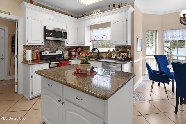 kitchen with white cabinetry, appliances with stainless steel finishes, a center island, and crown molding