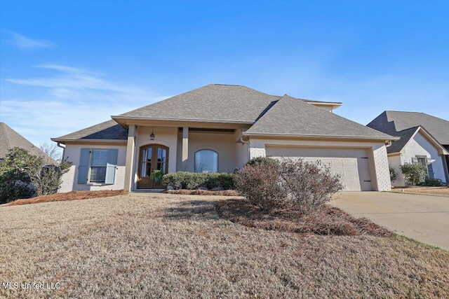 view of front facade with stucco siding, french doors, roof with shingles, concrete driveway, and a garage