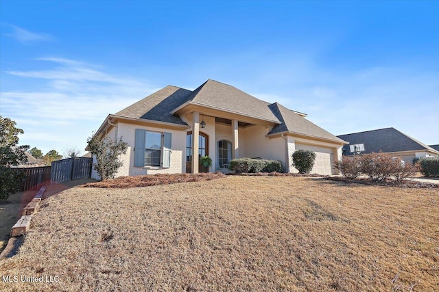 view of front of house featuring a shingled roof, fence, a front yard, stucco siding, and an attached garage