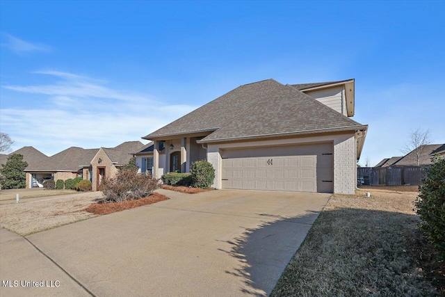 view of front of house with concrete driveway, a garage, and a shingled roof