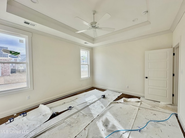 unfurnished room featuring ceiling fan, ornamental molding, a raised ceiling, and light hardwood / wood-style flooring