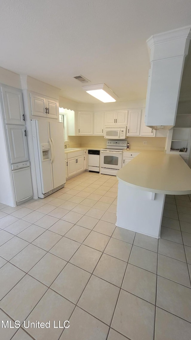 2257 Boyd Rd, Utica, MS 39175 - kitchen featuring white appliances, a peninsula, light countertops, light tile patterned floors, and white cabinetry
