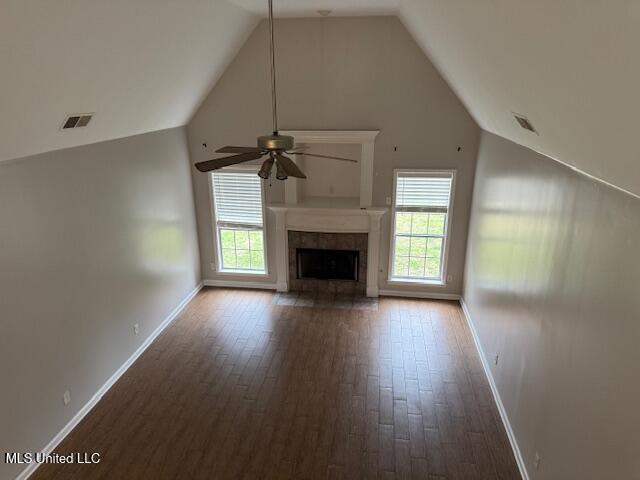 unfurnished living room with a healthy amount of sunlight, high vaulted ceiling, a fireplace, and visible vents