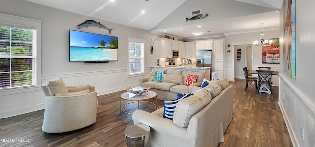 living room with visible vents, a wainscoted wall, dark wood-type flooring, an inviting chandelier, and vaulted ceiling