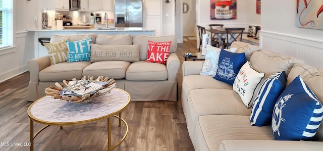 living area with wainscoting and wood finished floors