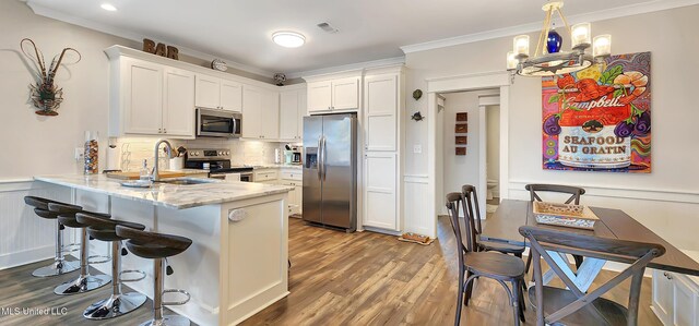 kitchen featuring appliances with stainless steel finishes, white cabinets, a sink, and ornamental molding