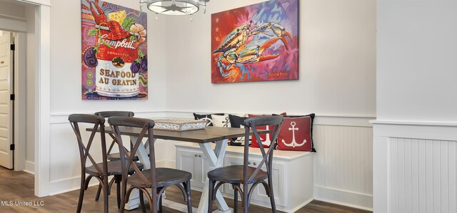 dining space featuring a wainscoted wall, dark wood-type flooring, and breakfast area