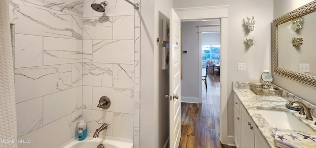 bathroom with washtub / shower combination, baseboards, wood finished floors, and vanity