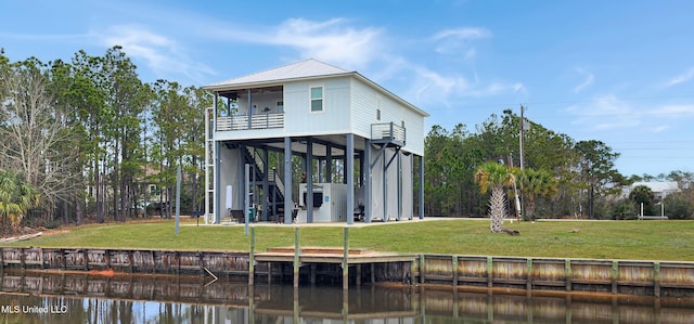 rear view of house with a carport, a balcony, a water view, and a lawn