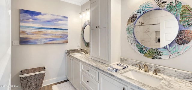 full bath featuring double vanity, baseboards, a sink, and wood finished floors