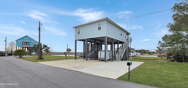 view of front of house featuring a carport, a front lawn, stairway, and concrete driveway