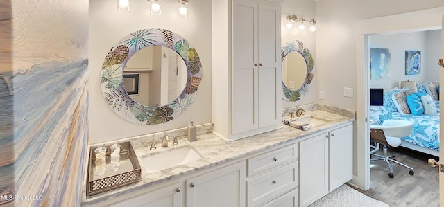 full bathroom with double vanity, connected bathroom, a sink, and wood finished floors