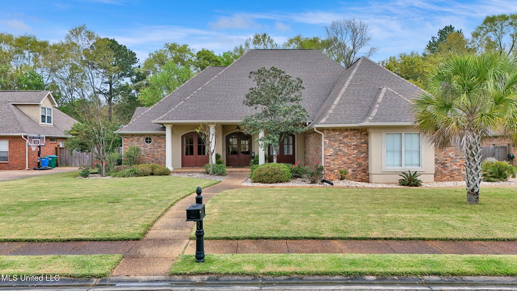 view of front facade with brick siding, fence, roof with shingles, and a front lawn