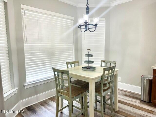 dining area featuring crown molding, hardwood / wood-style flooring, and a chandelier