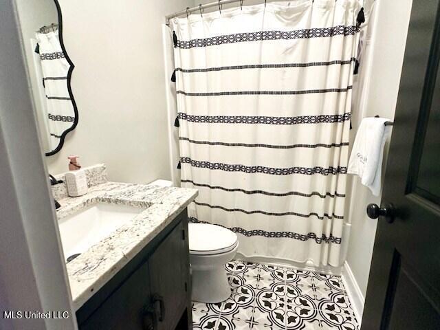 bathroom with tile patterned floors, vanity, toilet, and curtained shower