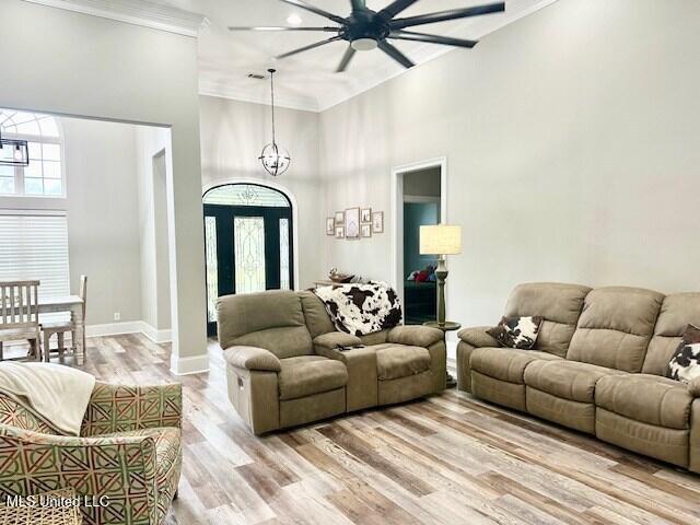 living room featuring a high ceiling, crown molding, a notable chandelier, and light wood-type flooring