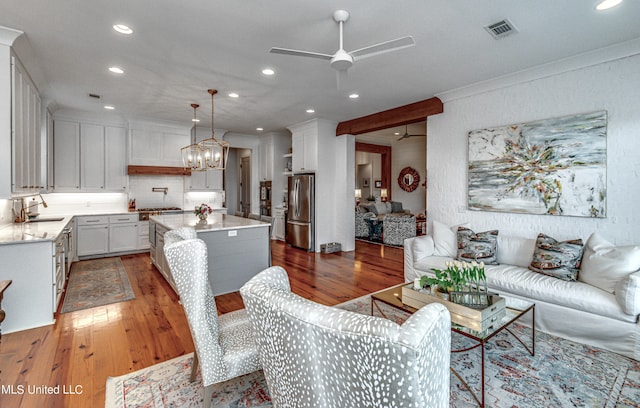 living room with ornamental molding, sink, ceiling fan with notable chandelier, and dark hardwood / wood-style flooring