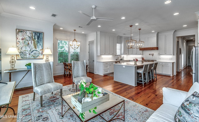 living room featuring sink, dark wood-type flooring, and ceiling fan with notable chandelier