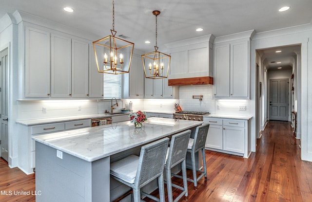 kitchen with a kitchen island, light stone countertops, pendant lighting, white cabinetry, and dark hardwood / wood-style flooring