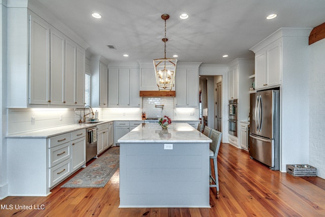 kitchen with a center island, appliances with stainless steel finishes, light hardwood / wood-style flooring, and white cabinets