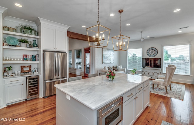 kitchen featuring white cabinets, beverage cooler, a kitchen island, stainless steel refrigerator, and light hardwood / wood-style floors