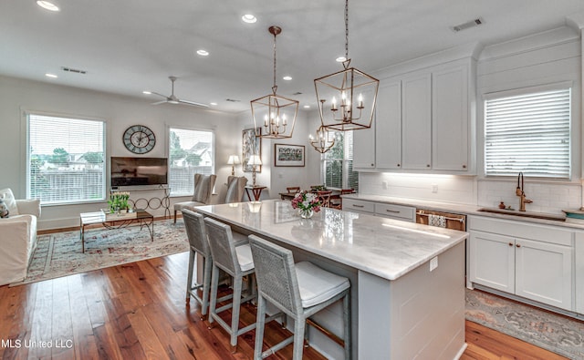 kitchen featuring light hardwood / wood-style flooring, backsplash, a center island, a kitchen bar, and white cabinetry