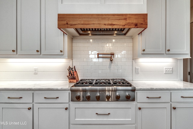 kitchen featuring extractor fan, stainless steel gas stovetop, tasteful backsplash, and light stone countertops