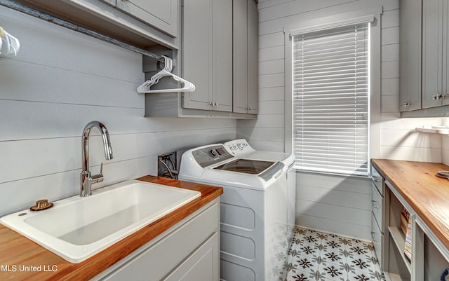 washroom featuring cabinets, sink, separate washer and dryer, and wooden walls