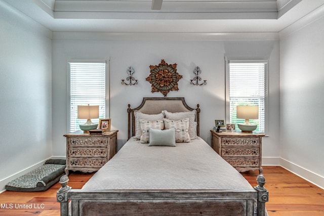 bedroom featuring hardwood / wood-style floors, crown molding, and multiple windows