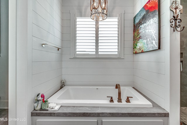 bathroom featuring an inviting chandelier and a tub