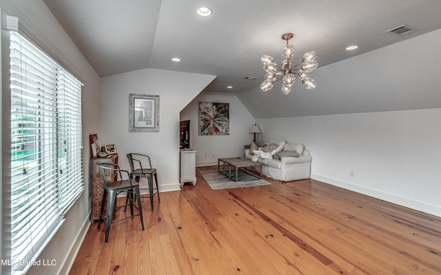 sitting room featuring a chandelier, vaulted ceiling, and light wood-type flooring