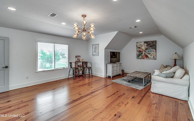 sitting room featuring vaulted ceiling, wood-type flooring, and an inviting chandelier