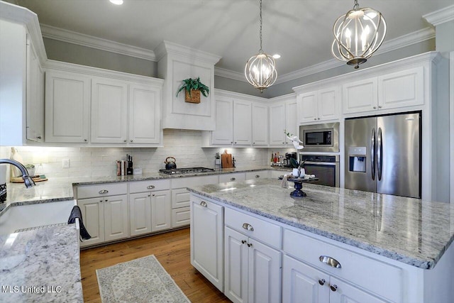 kitchen featuring light stone countertops, stainless steel appliances, pendant lighting, white cabinets, and light hardwood / wood-style flooring