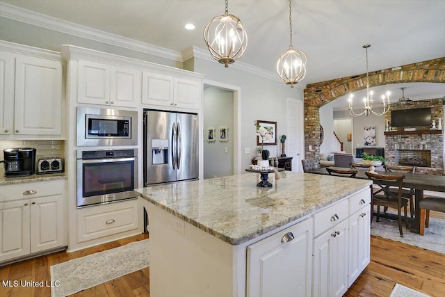 kitchen featuring appliances with stainless steel finishes, a kitchen island, hanging light fixtures, light hardwood / wood-style floors, and white cabinets