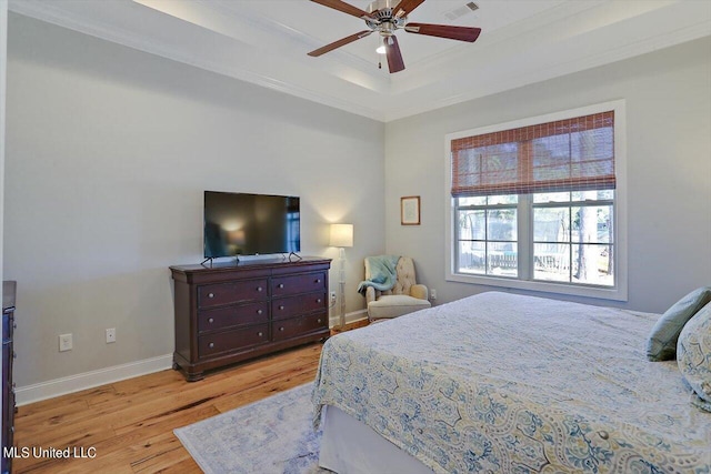 bedroom featuring ceiling fan, crown molding, a tray ceiling, and light hardwood / wood-style floors