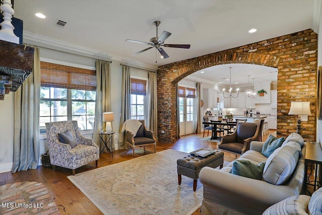 living room featuring ornamental molding, dark hardwood / wood-style flooring, plenty of natural light, and ceiling fan with notable chandelier