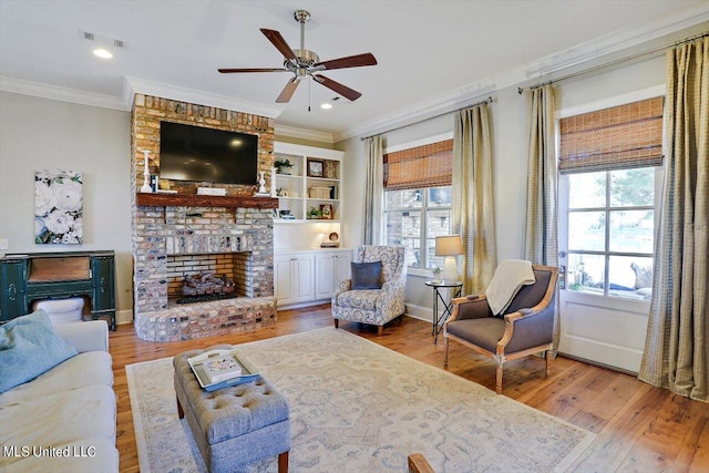 living room with ornamental molding, hardwood / wood-style flooring, a fireplace, and ceiling fan