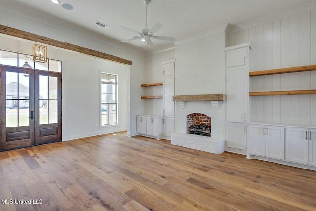 unfurnished living room featuring light wood-style flooring, a fireplace, visible vents, a ceiling fan, and crown molding