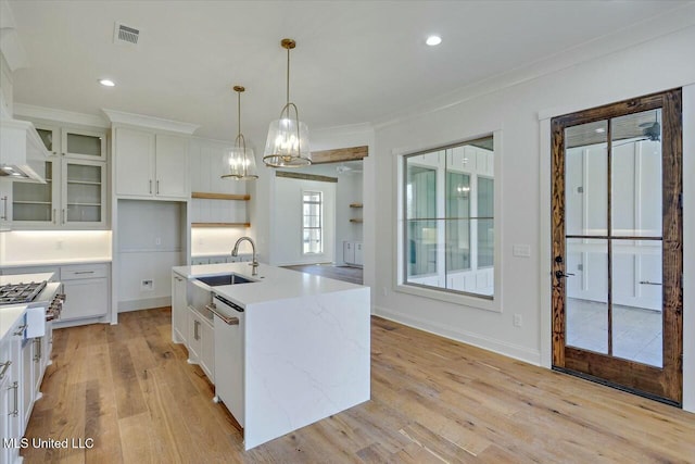 kitchen with pendant lighting, open shelves, appliances with stainless steel finishes, white cabinetry, and a sink