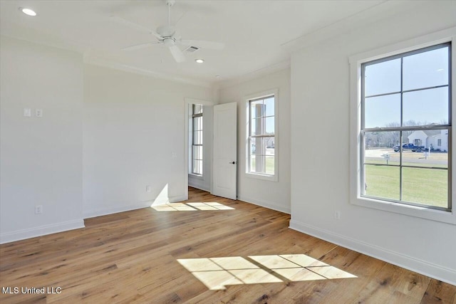 spare room with a healthy amount of sunlight, light wood-style floors, and ornamental molding