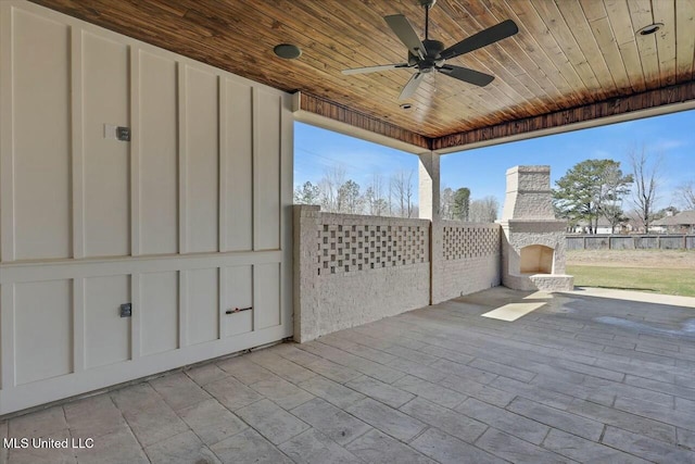 view of patio with an outdoor stone fireplace and a ceiling fan